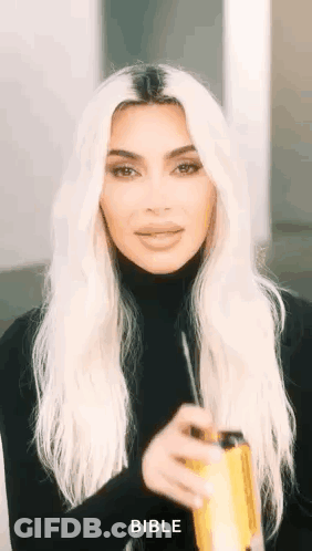 Kim Kardashian Is Wearing A Black Turtleneck And Holding A Can Of Soda In Her Hand . GIF
