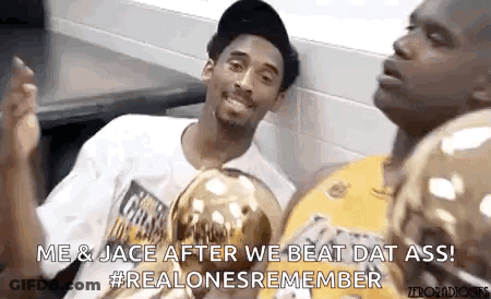 Kobe Bryant And Shaquille O'neal Are Sitting Next To Each Other In A Locker Room With Trophies . GIF