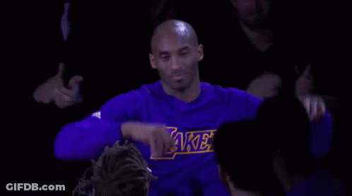 Kobe Bryant Is Wearing A Purple Lakers Shirt While Sitting In The Stands During A Game . GIF