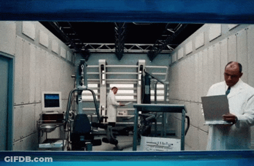 Lab Coat Man Checking Clipboard Colleague Working On Machine GIF