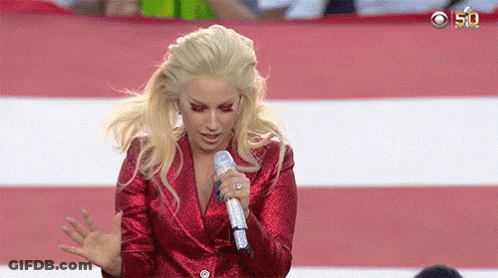 Lady Gaga Is Singing Into A Microphone While Wearing A Red Jacket . GIF