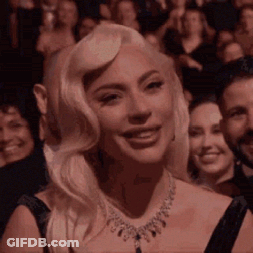 Lady Gaga Is Smiling While Sitting In A Crowd Of People . GIF