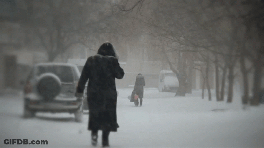 Lady In Trench Coat Walking In Snow Storm GIF