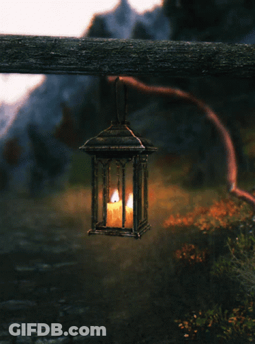 Lantern With Lit Candle Hanging From Wooden Post GIF