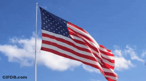 Large American Flag Flying In Blue Sky GIF