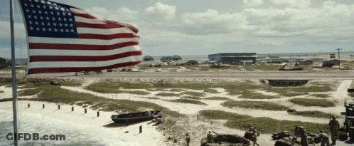 Large American Flag Flying Over Small Island GIF