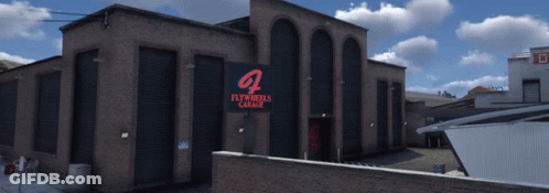 Large Brick Building With Flywheels Garage Sign GIF