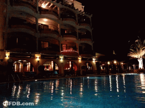 Large Building With Swimming Pool At Night GIF