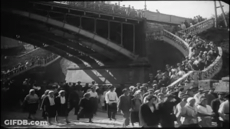 Large Crowd Walking Under Bridge GIF
