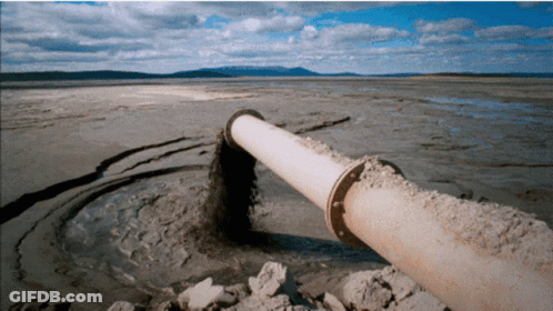 Large Pipe Pouring Sand Into Rocky Water GIF