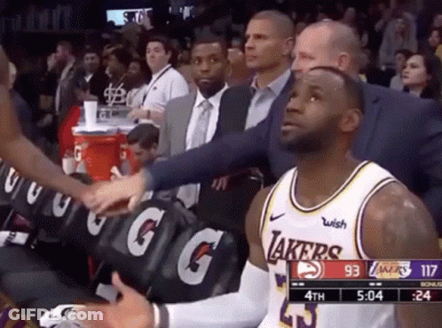 Lebron James Is Sitting In The Stands During A Basketball Game While A Man Shakes His Hand . GIF