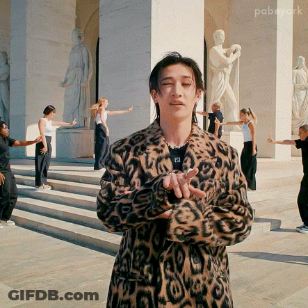 Leopard Coat Man Holding Microphone To Ponytail Woman GIF