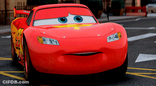 Lightning Mcqueen From The Movie Cars Is Driving Down A Street GIF