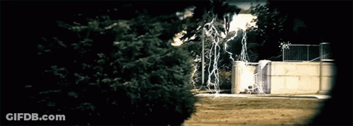 Lightning Strikes Behind Fence And Trees GIF