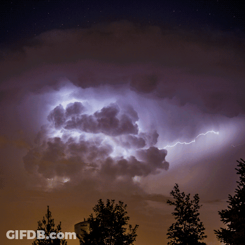 Lightning Strikes In A Cloudy Night Sky With A Sign In The Foreground GIF