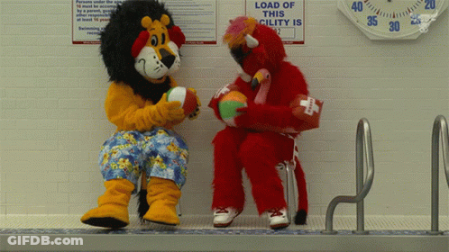 Lion And Flamingo Mascot Sitting Near Load Of This Cility Sign GIF