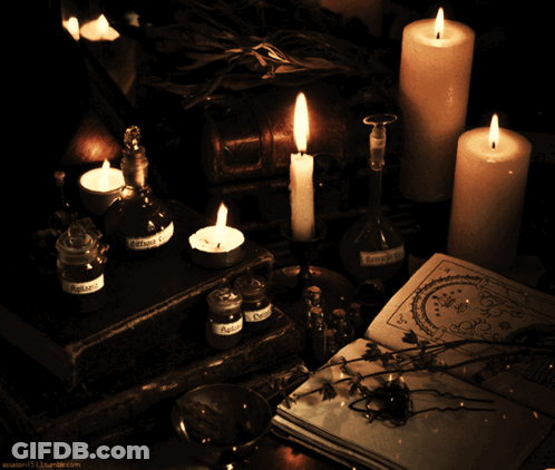 Lit Candles On Table With Potions And Book GIF