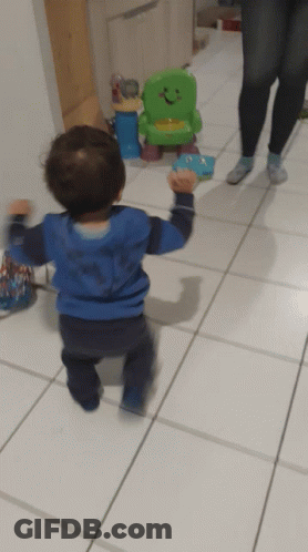 Little Boy In Blue Shark Shirt Walking To Green Toy Chair GIF