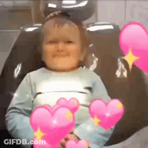 Little Boy In Chair With Pink Hearts Necklace GIF