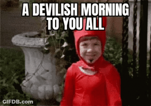 Little Boy In Red Devil Costume Standing In Front Of White Vase GIF