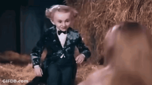 Little Boy In Suit And Bow Tie Next To Woman In Haystack GIF