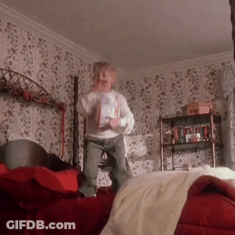 Little Boy Jumping On Bed Holding Book GIF