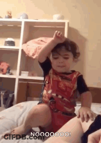 Little Boy Sitting On Bed Hand Up GIF