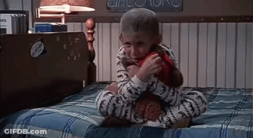 Little Boy Sitting On Bed With Stuffed Animal GIF