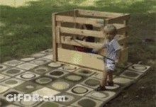 Little Boy Standing In Front Of Wooden Playhouse GIF