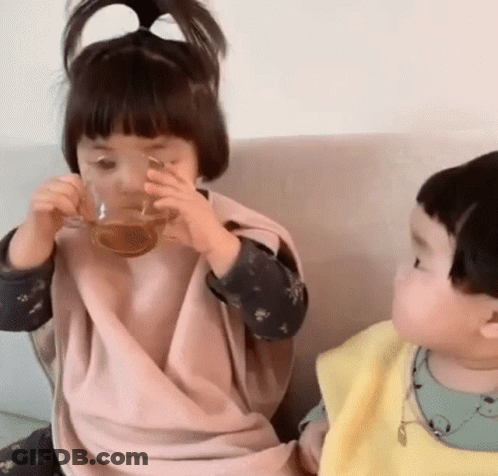 Little Girl Drinking From Glass Next To Boy GIF