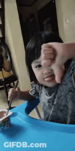 Little Girl Eating Yogurt With Spoon Giving Thumbs Down GIF