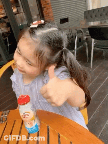 Little Girl Giving Thumbs Up At Table GIF