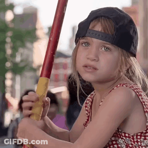 Little Girl In Black Hat Holding Red And Yellow Stick GIF