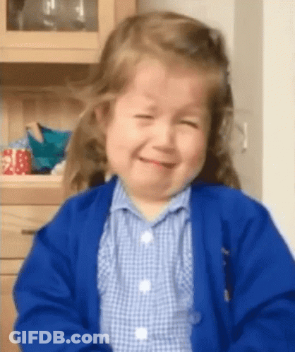 Little Girl In Blue Cardigan And Plaid Shirt Smiling GIF