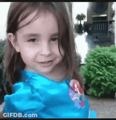 Little Girl In Blue Dress Smiling In Front Of House GIF