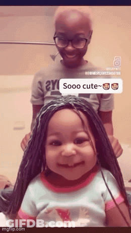 Little Girl In Braided Wig Smiling Next To Boy With Glasses GIF