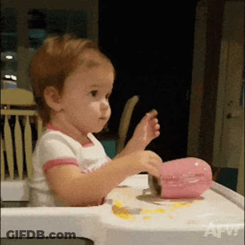 Little Girl In High Chair Playing With Pink Object GIF