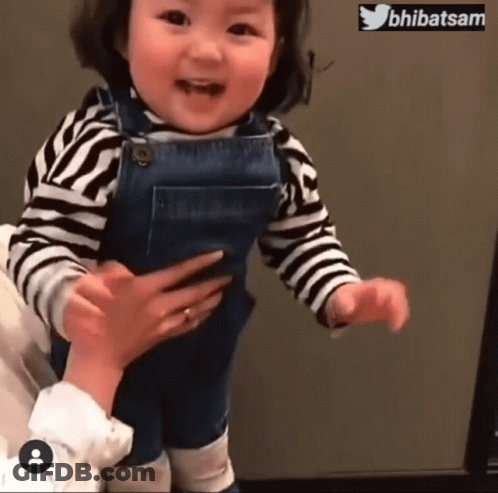Little Girl In Overalls And Striped Shirt Being Held GIF
