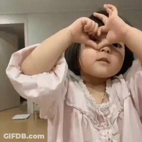 Little Girl In Pink Dress Making Heart Shape GIF