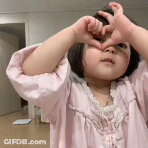 Little Girl In Pink Dress Making Heart With Hands GIF