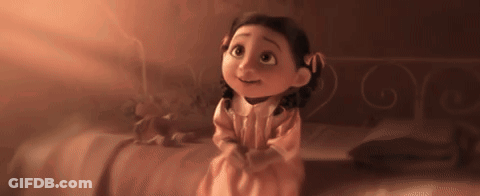 Little Girl In Pink Dress Sitting On Bed Looking Up GIF