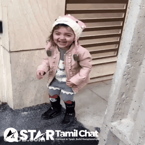 Little Girl In Pink Jacket And Hat In Front Of Tamil Chat Sign GIF