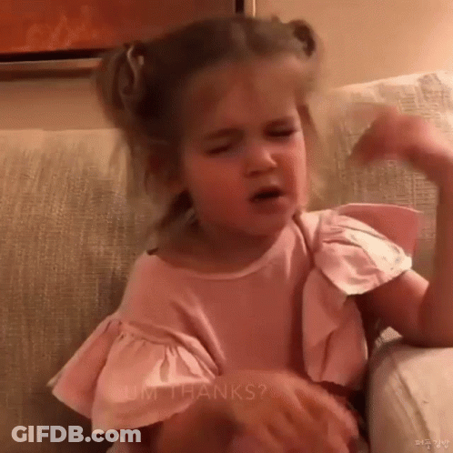 Little Girl In Pink Shirt Sitting On Couch Making Face GIF
