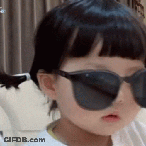 Little Girl In Sunglasses Sitting On Couch GIF