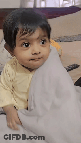 Little Girl Laying On Bed With Remote Control GIF
