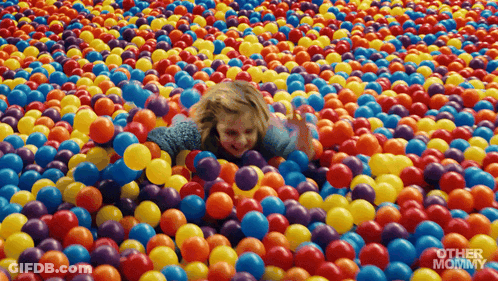Little Girl Lying In Colorful Plastic Balls GIF