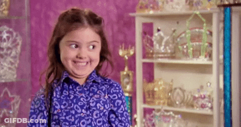 Little Girl Making Funny Face In Front Of Tiara Shelf GIF