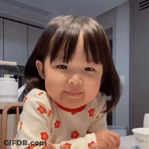 Little Girl Making Funny Face In Kitchen GIF