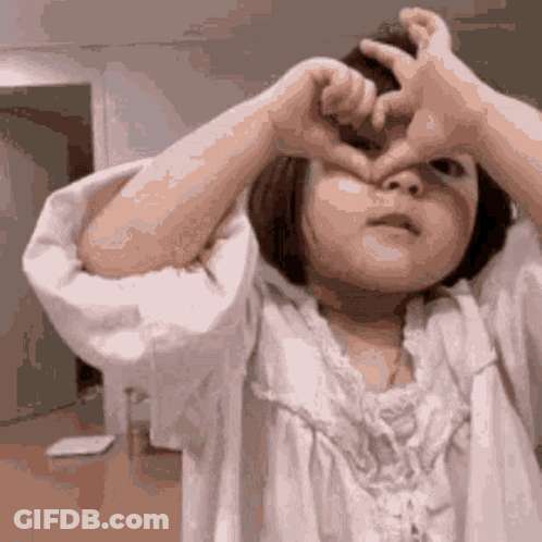 Little Girl Making Heart With Hands Over Eyes GIF