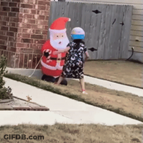 Little Girl Next To Large Inflatable Santa Claus GIF